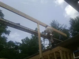 Carpenter setting a ridge beam over a new addition frame — Ice Dam Removal by Roofing Brothers in Okemos