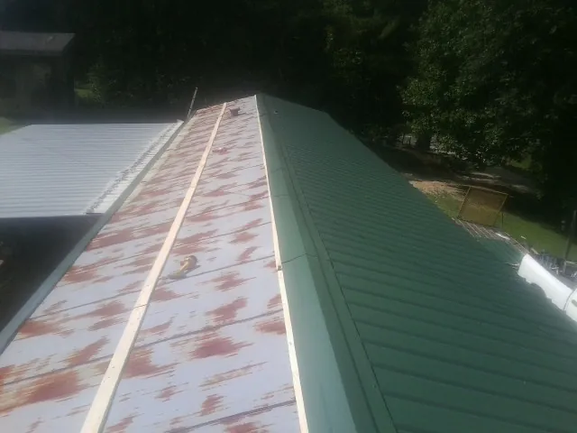 Old rusted panels beside newly installed green metal roofing — Wind Damage Roof Repair by Roofing Brothers in Okemos