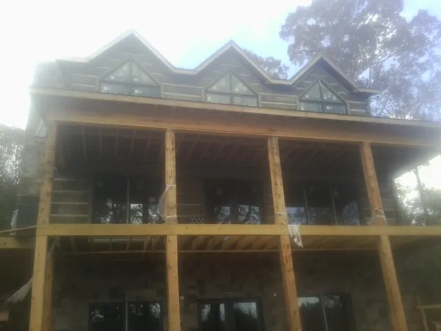 Dormers and porch framing on a large log home under construction — Roof Coating work by our crew in Okemos
