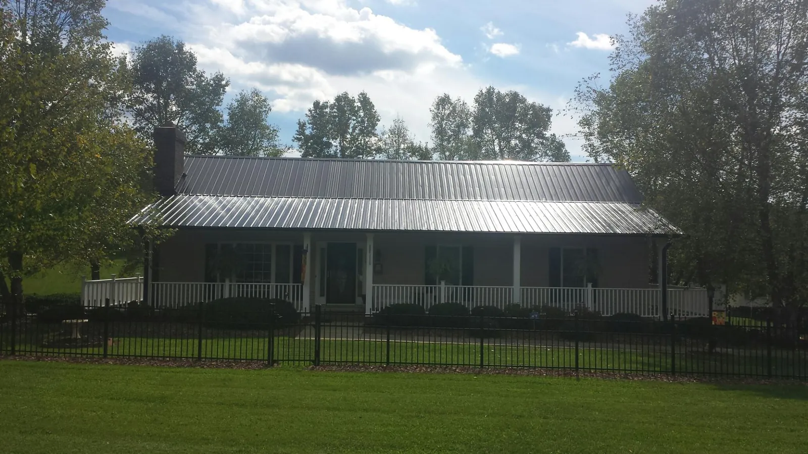 Gray metal roof on a brick ranch with a full width front porch — Gutter Guard Installation work by our crew in Okemos