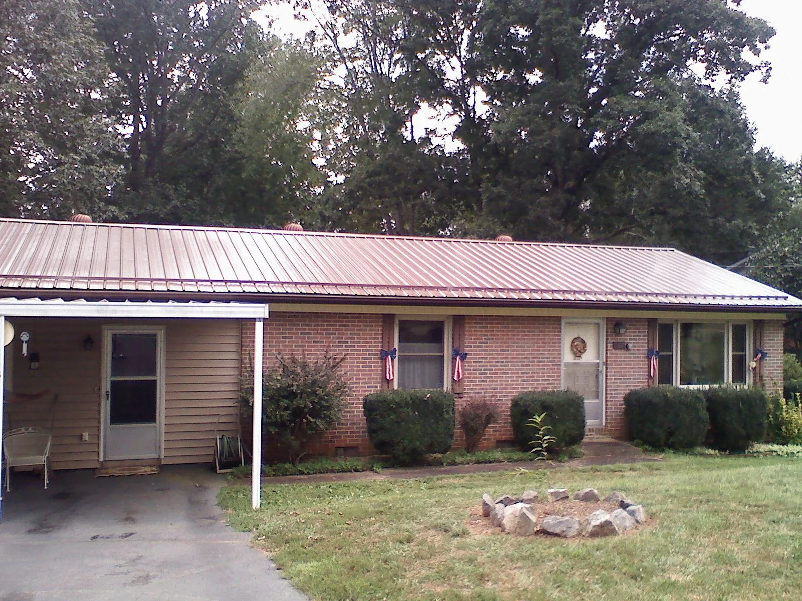 Bronze metal roof and carport on a brick ranch home — Roof Repair work by our crew in Okemos